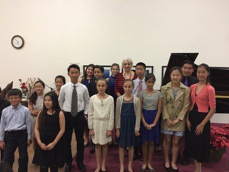 Students of the Russian School of Piano gathered by a grand piano after a recital